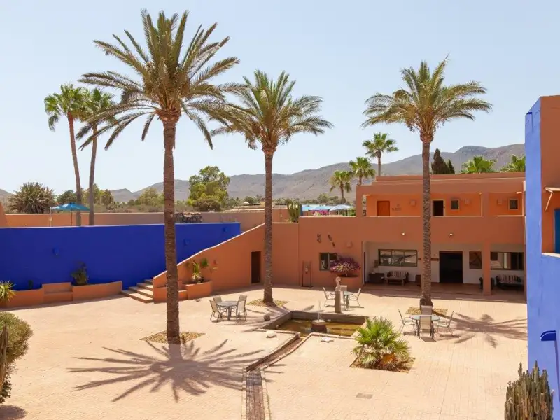 Innenhof des Hotels mit Palmen, Springbrunnen und bunten Gebäuden.