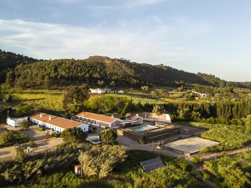 Luftansicht der Unterkunft mit Pool, Sportplatz und umgebenden Hügeln.