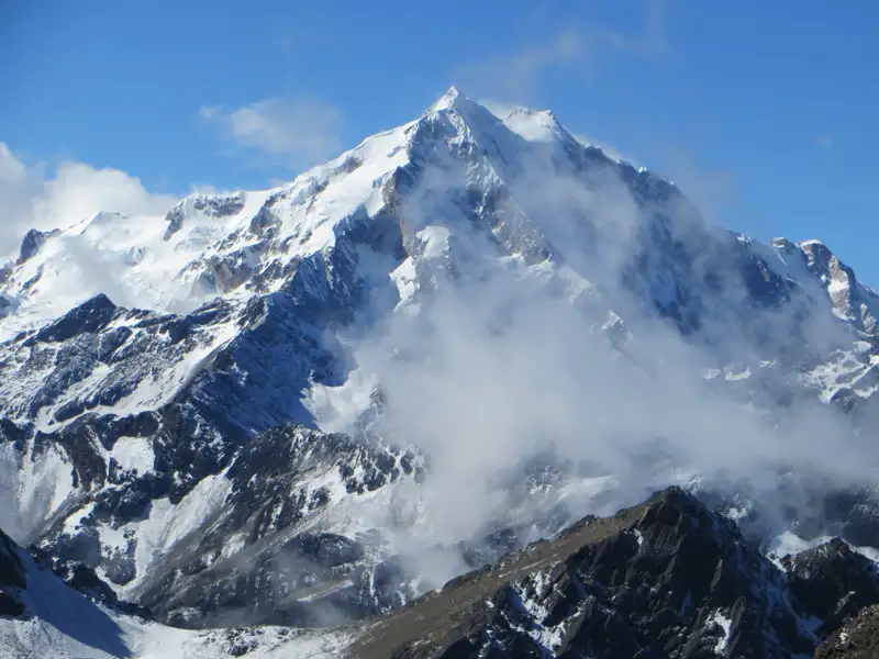 Schneebedeckter Berggipfel mit Wolken.