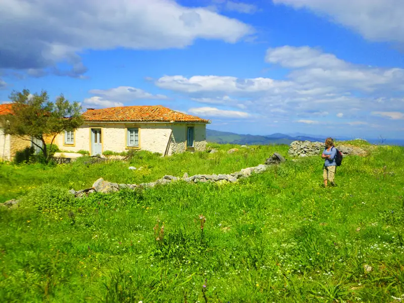 Wanderer auf einer Wiese vor einem Haus.