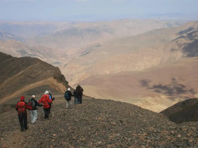 Wanderer auf einem Bergpfad in einer bergigen Landschaft.