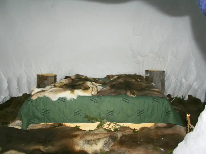 Schlafplatz im Iglu mit Fellen und Decke.
