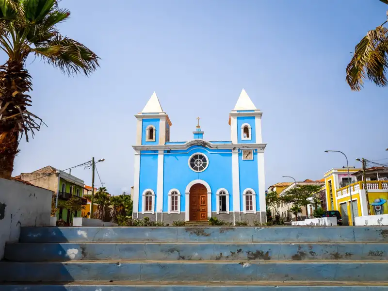 Blaue Kirche mit weißen Verzierungen und zwei Türmen.