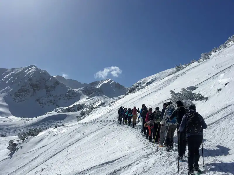 Gruppe von Schneeschuhwanderern auf einem verschneiten Bergpfad.