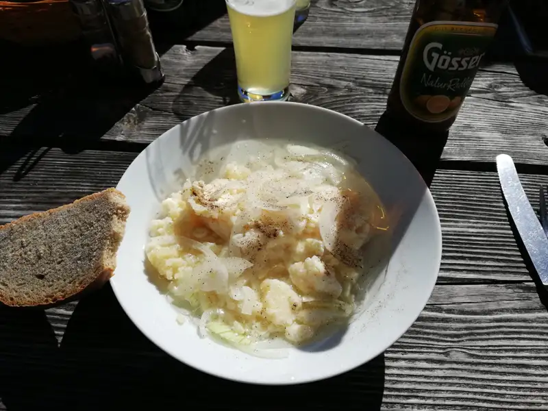 Kartoffelsalat mit Zwiebeln und Brot, begleitet von einem Gösser NaturRadler.