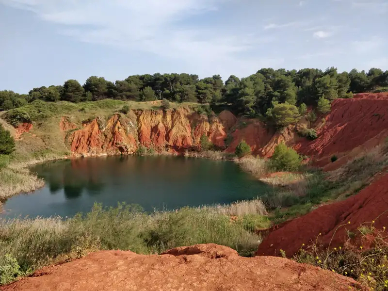 See mit roten und orangefarbenen Felsformationen.