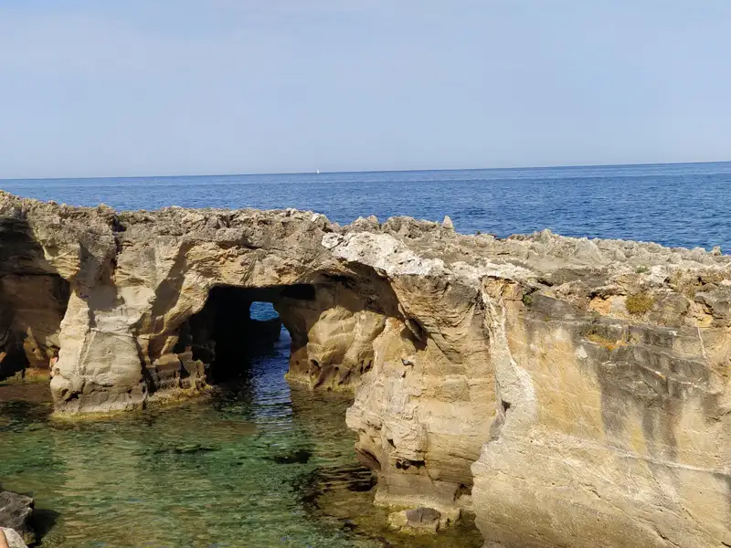 Erodierte Küstenfelsen mit einem natürlichen Bogen und Blick aufs Meer.