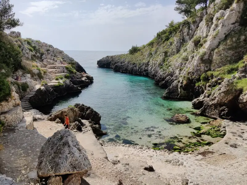 Klares, türkisfarbenes Wasser in einer felsigen Bucht.