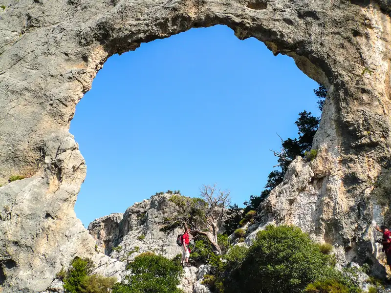 Wanderer erkundet einen natürlichen Felsbogen auf einer Wanderung.