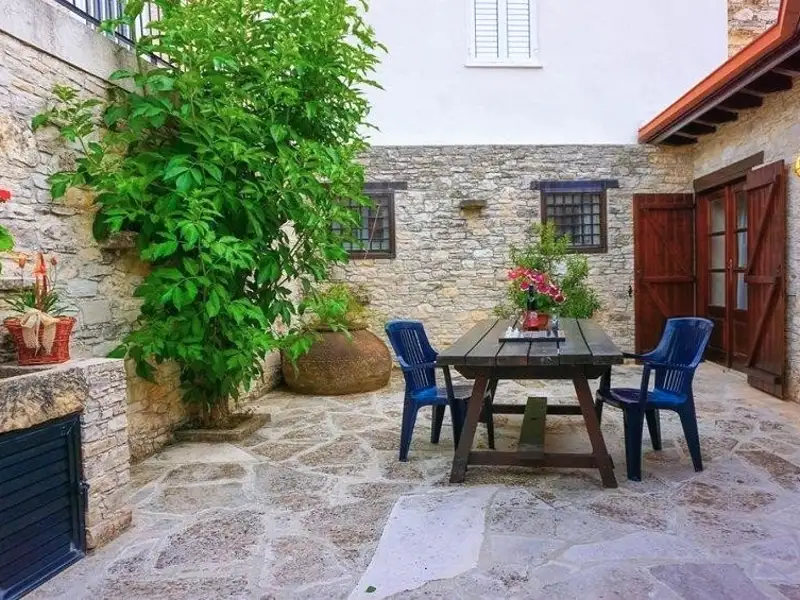 Innenhof mit Steinboden, Tisch, Stühlen und Pflanzen.