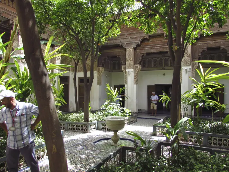 Traditioneller Innenhof mit Bäumen, Springbrunnen und dekorativen Elementen.