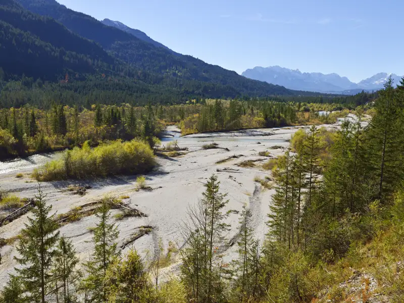 Flusslandschaft mit Bergen im Hintergrund.