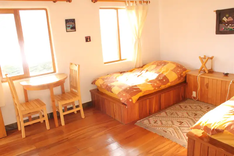 Zwei Einzelbetten in einem hellen Zimmer mit Holzboden und Tisch.