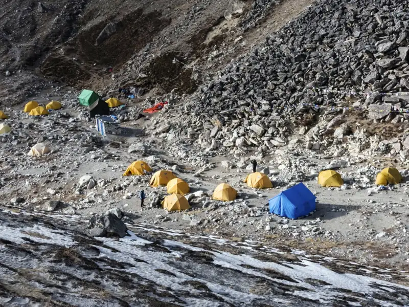 Basislager mit Zelten in einer steinigen Gebirgslandschaft.