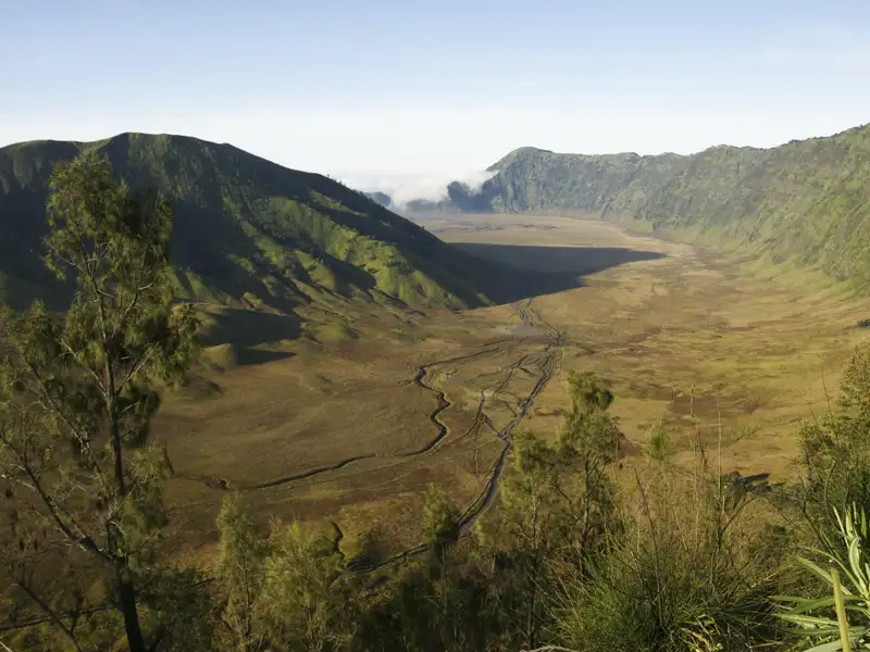 Panoramablick auf ein Tal inmitten grüner Hügel.