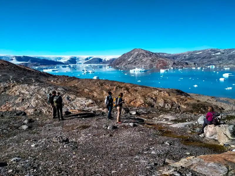 Wanderer auf einer Wanderung mit Blick auf einen Fjord voller Eisberge.