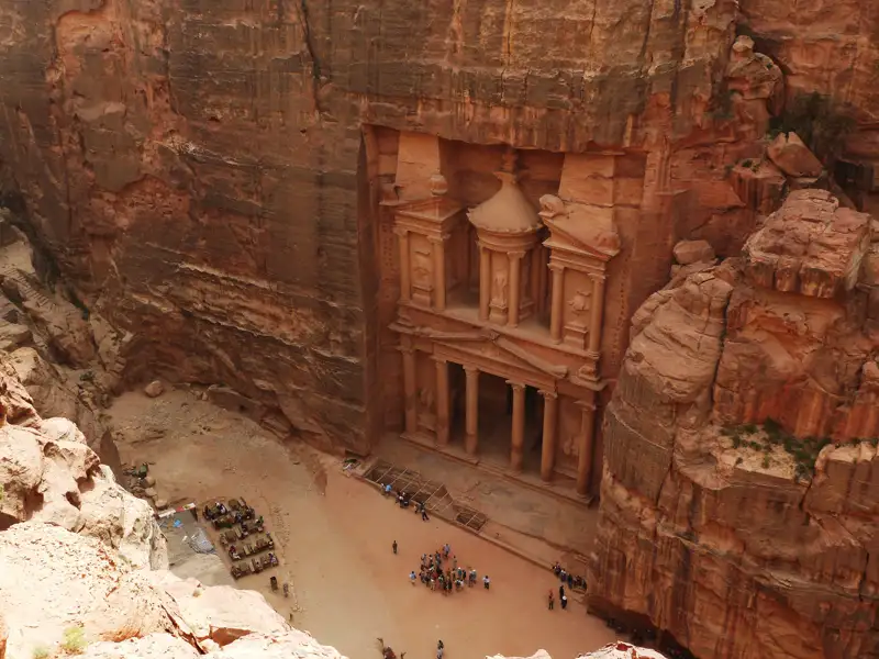 Das Schatzhaus in Petra, Jordanien, aus einer erhöhten Perspektive. Touristen erkunden den Bereich vor dem Monument.