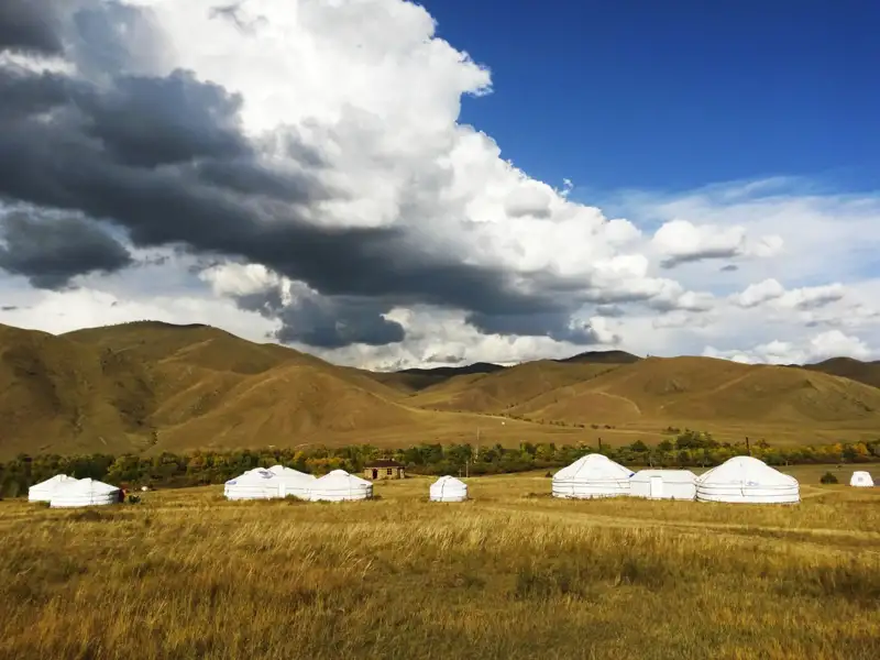 Traditionelle Jurtenunterkünfte inmitten einer hügeligen Landschaft.