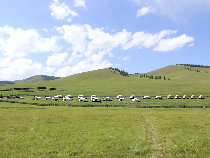 Jurtenunterkünfte, umgeben von grünen Hügeln.