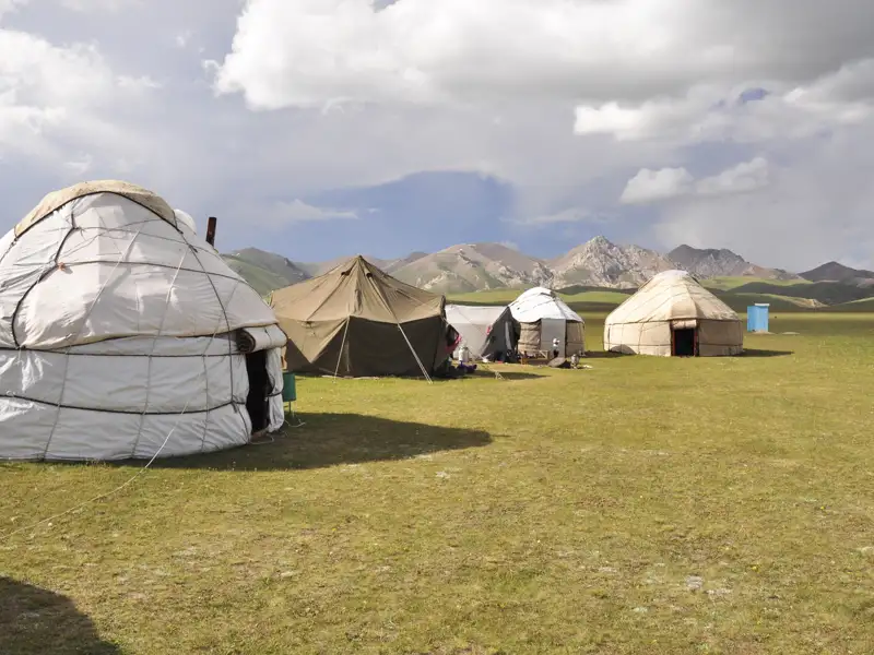 Jurtenunterkünfte in einer Bergregion, möglicherweise Teil einer kulturellen Reiseerfahrung.