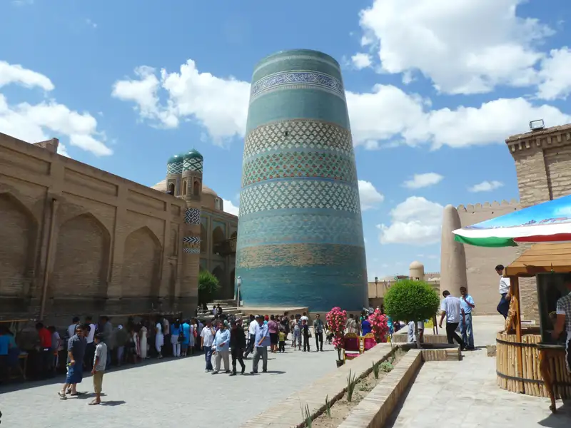 Blick auf das Kalta-Minor-Minarett in Chiwa mit Besuchern im Vordergrund.
