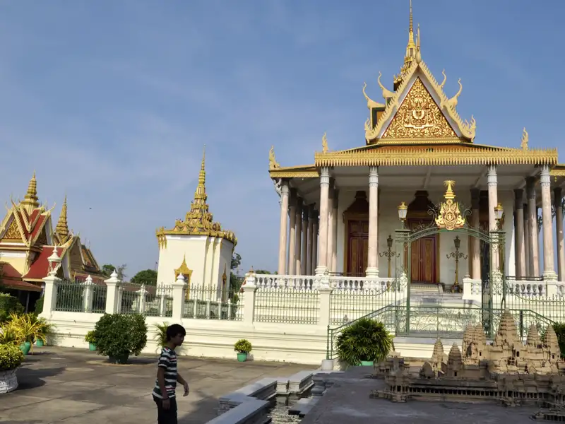 Ein traditionelles Tempelgebäude mit goldenen Verzierungen und ein Modell von Angkor Wat, welches die kulturelle Bedeutung der Tempelanlage unterstreicht.
