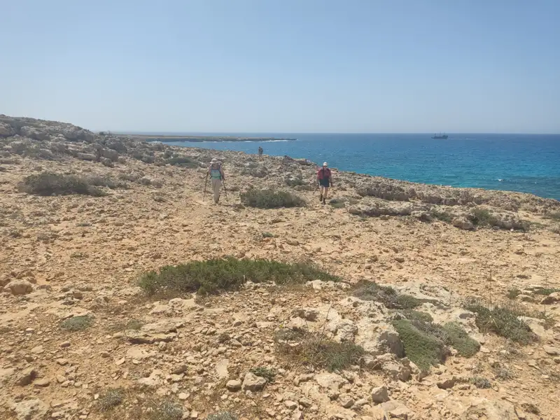 Wanderer auf einem felsigen Küstenpfad mit Blick auf das Meer.