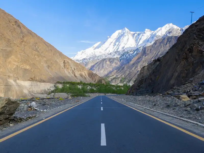 Straße durch eine Berglandschaft mit schneebedeckten Gipfeln.