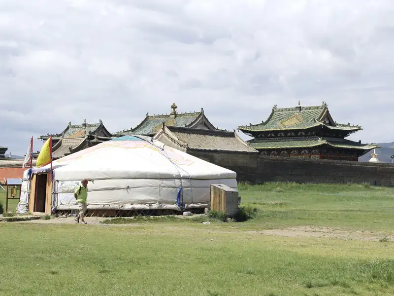 Traditionelle mongolische Jurte vor einem Tempelgebäude.
