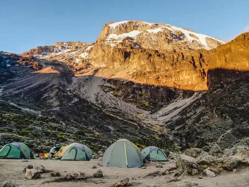 Basislager mit Zelten vor einem schneebedeckten Berg.