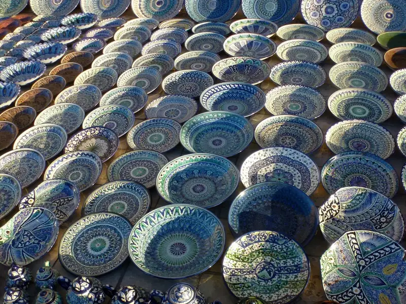 Handbemalte Keramikteller mit blauen und grünen Mustern, ausgestellt auf einem Markt.