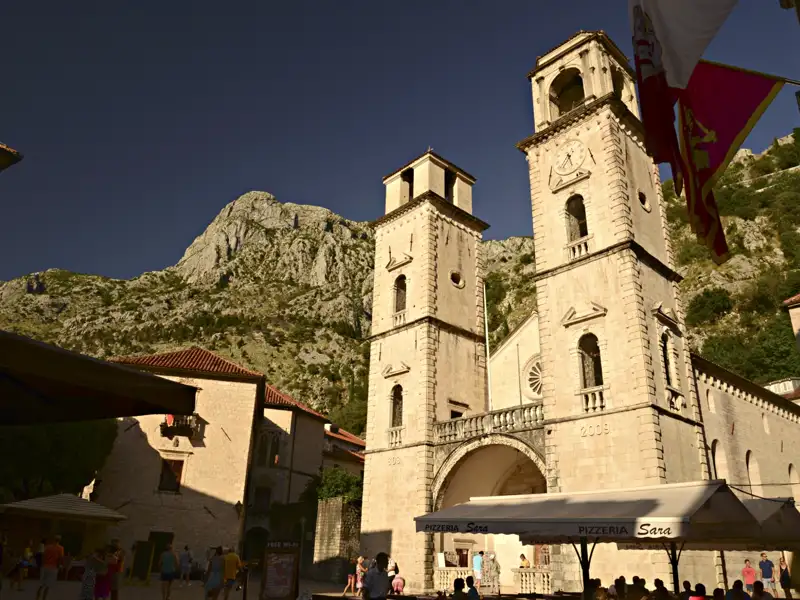 Kirche mit zwei Glockentürmen und einem Berg im Hintergrund.