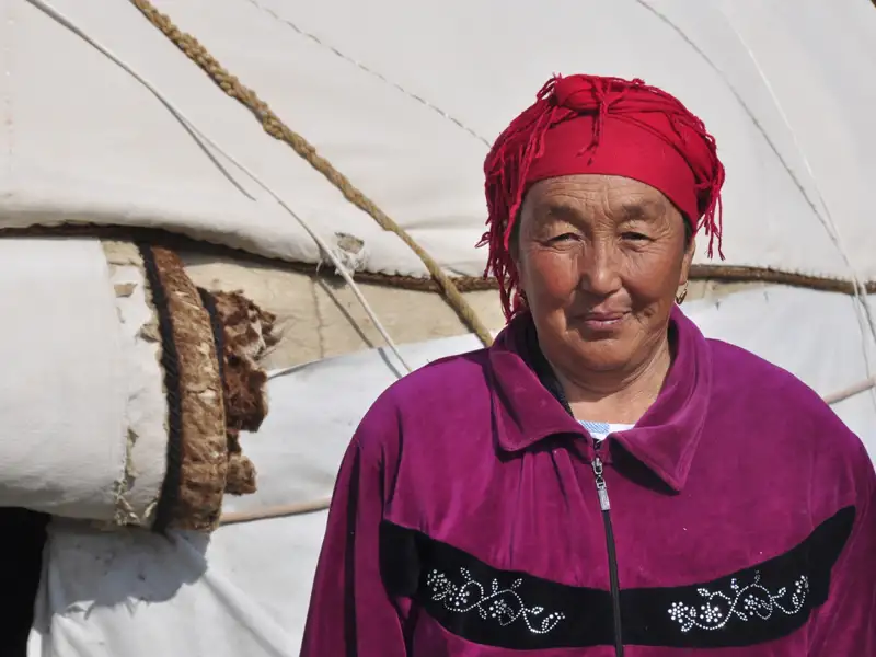 Frau in traditioneller Kleidung vor einer Jurte.