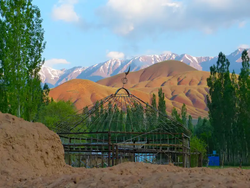 Metallgerüst einer Jurte mit Berglandschaft im Hintergrund.