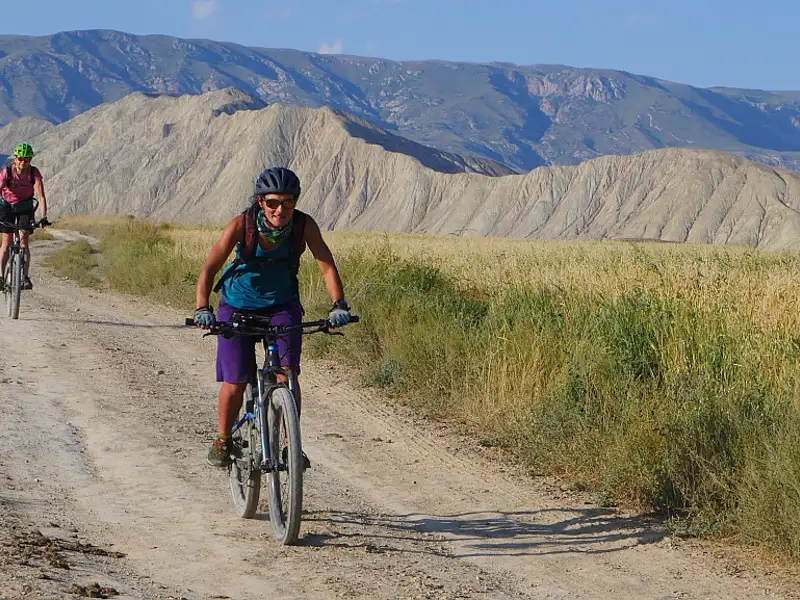 Radfahrer auf einem unbefestigten Weg in bergigem Gelände.