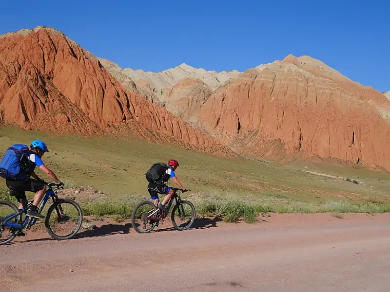 Zwei Mountainbiker auf einer Radtour durch eine Landschaft mit roten Felsformationen.