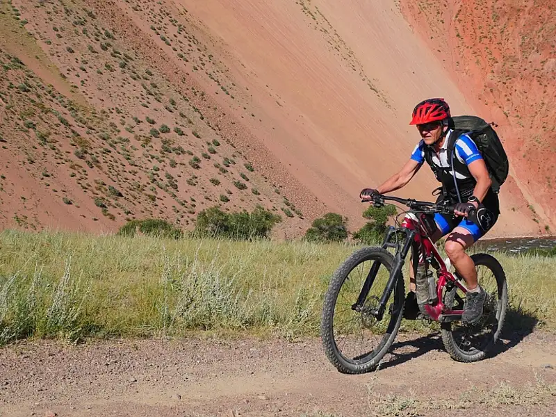 Mountainbiker auf einer Radtour entlang einer roten Felsformation.