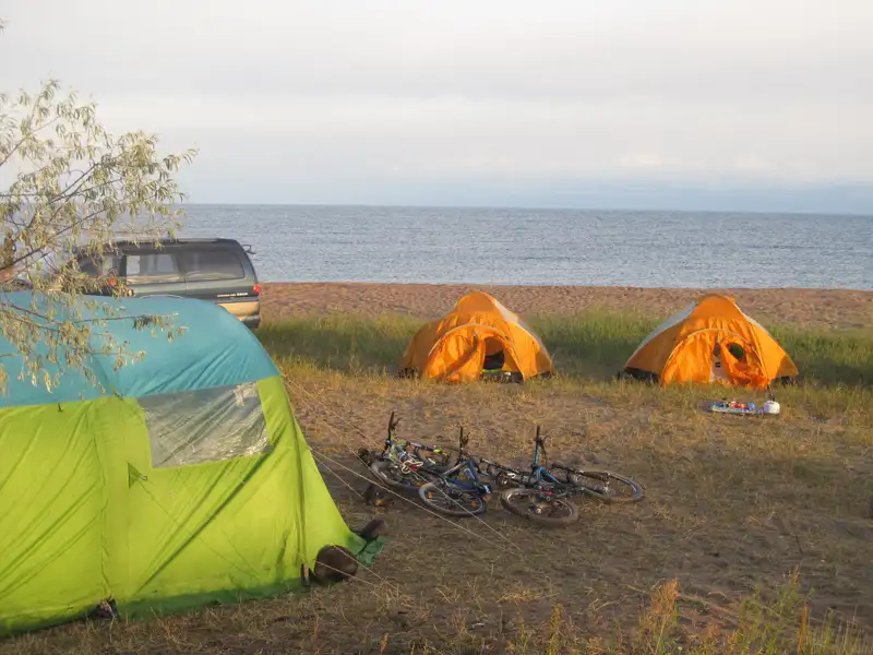 Campingplatz am Ufer mit zwei Zelten und Fahrrädern, bereit für eine Radtour.
