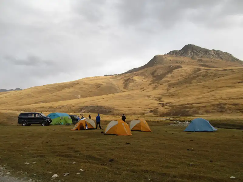 Campingplatz in den Bergen mit Zelten und einem Fahrzeug.