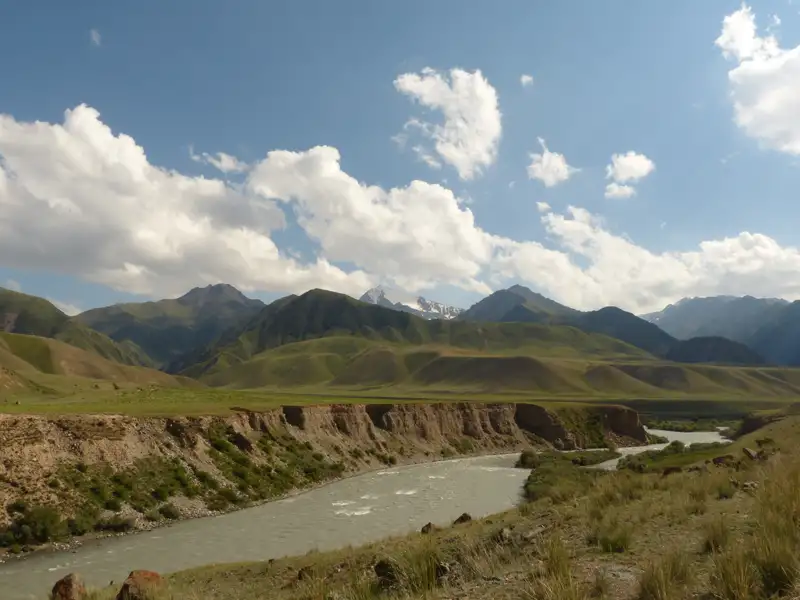 Blick auf einen Fluss, der durch ein Tal fließt, umgeben von Bergen.
