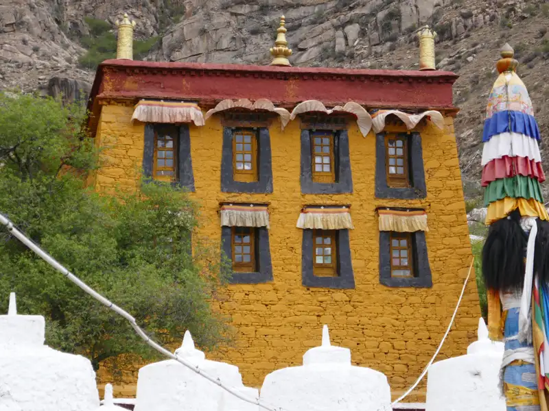 Gelbes Gebäude mit roten Dachziegeln und schwarzen Fensterrahmen, möglicherweise ein Kloster oder Tempel.