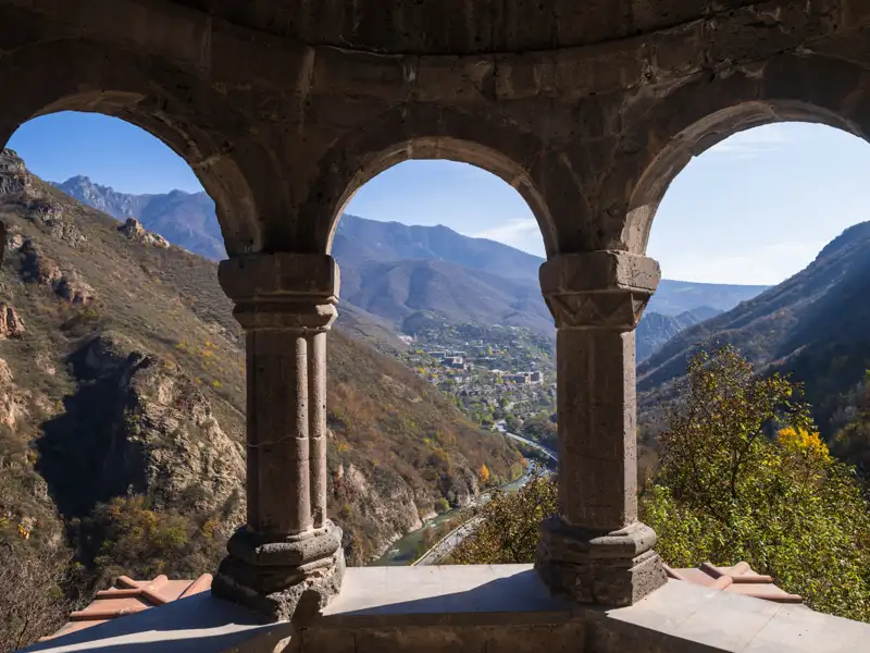 Panoramablick durch die Bögen eines historischen Gebäudes auf die umliegende Berglandschaft und das Tal.