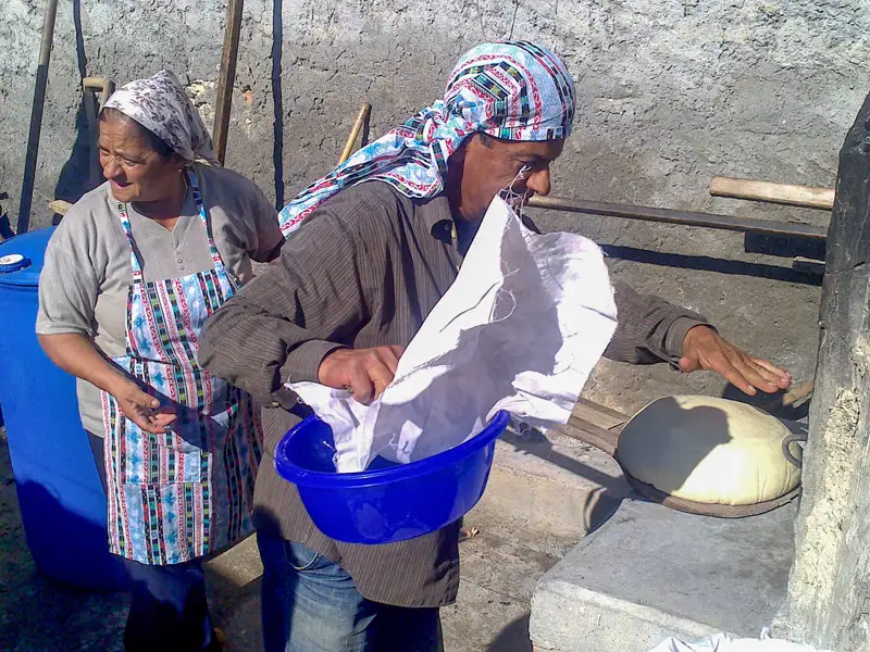Traditionelles Brotbacken: Ein Mann schiebt mit einem Tuch den Teig in einen Ofen, während eine Frau danebensteht.