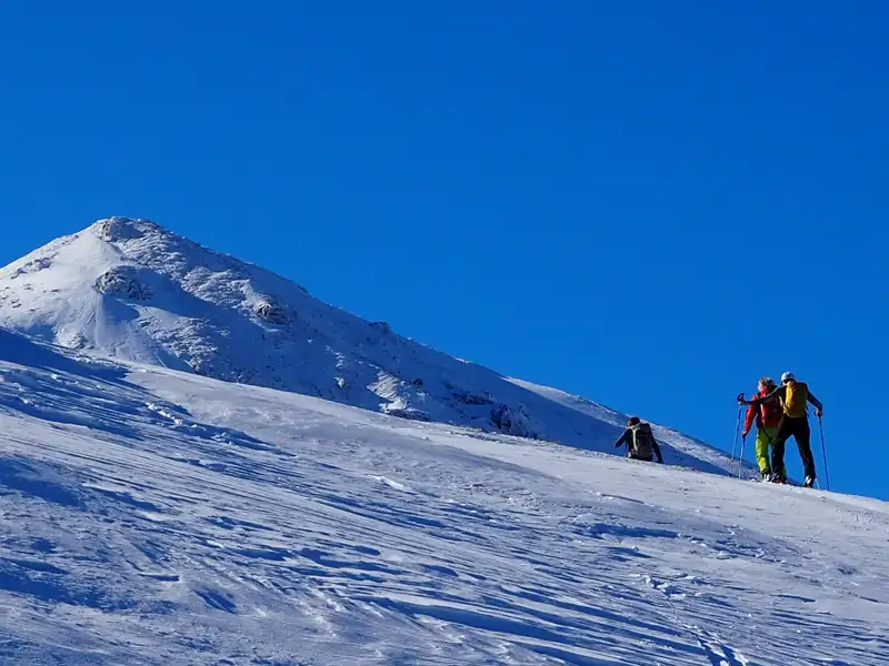 Skitourengeher besteigen einen Berg im Schnee.