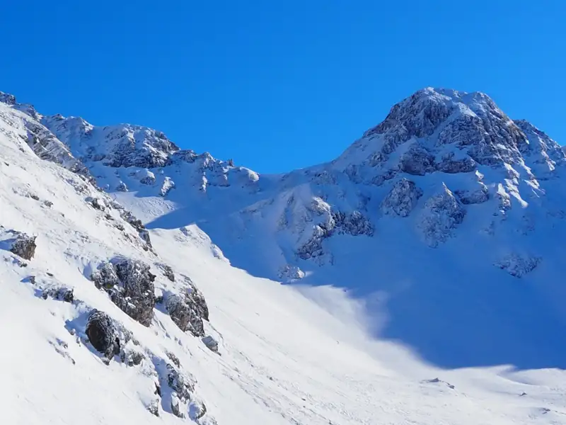 Verschneite Berglandschaft unter blauem Himmel.
