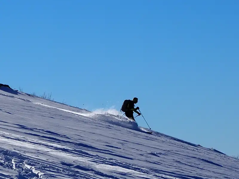 Skifahrer auf der Abfahrt im Schnee.