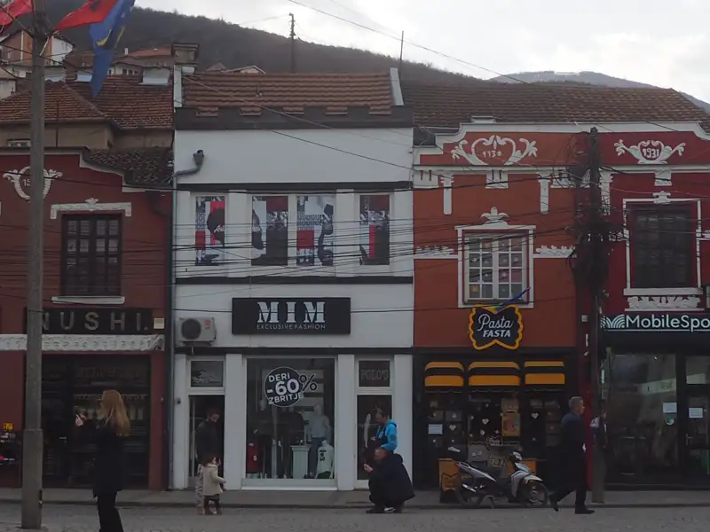 Ansicht verschiedener Geschäfte in einer Stadtstraße, darunter Mode, Pasta und Sushi.