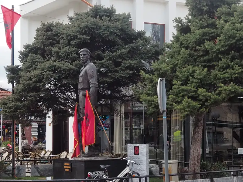 Statue eines Mannes in Uniform mit albanischen Flaggen.