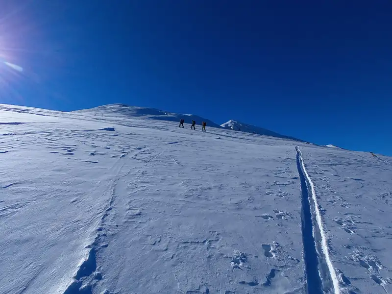 Skitourengeher auf dem Aufstieg eines verschneiten Berges.