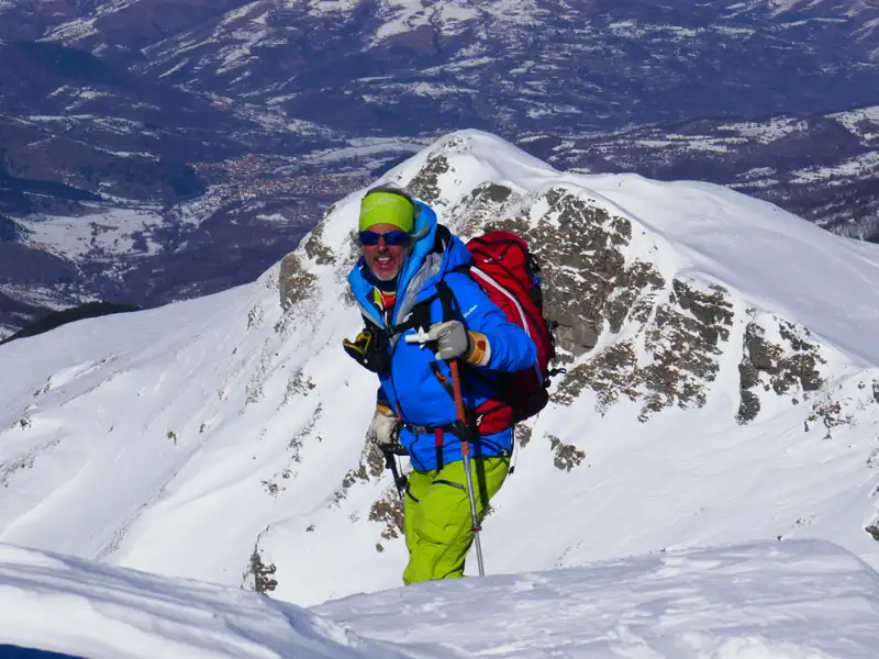 Skitourengeher auf einem verschneiten Berggipfel.